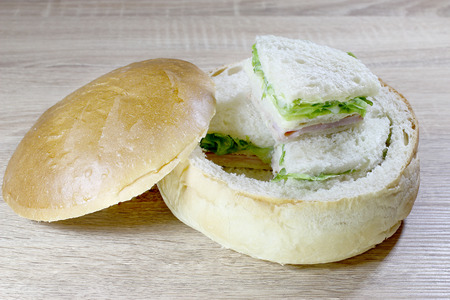 Sandwich box with chicken burger, tomatoes, ham, tuna, cheese on wood table.の写真素材