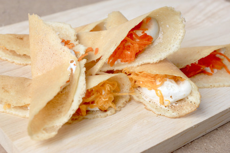 Thai pancake it is delicious snacks on wood background , Kind of Thai sweetmeat or Kanom Buang - Thai Style Crispy Tart or Thai sweetmeat with wood cutting board on wood backgroundの写真素材