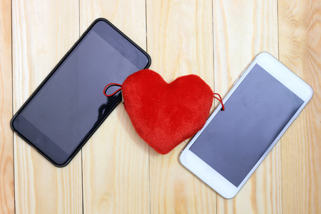 Smart phone with red hearts on wooden background, top viewの写真素材