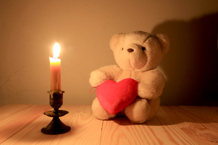 Teddy bear and red heart with candle light background, sill life styleの写真素材