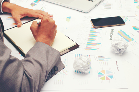 Businessman writing a business report on blank notebook with red pen on desk office. .Business concept:の写真素材