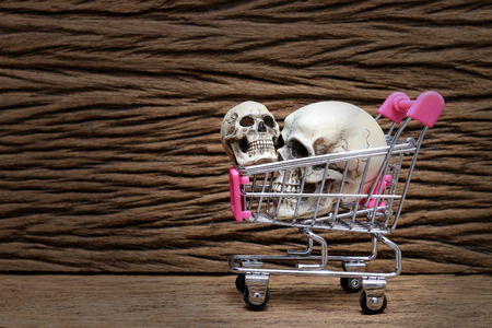Human skull in shopping car on old beautiful wooden background.の写真素材