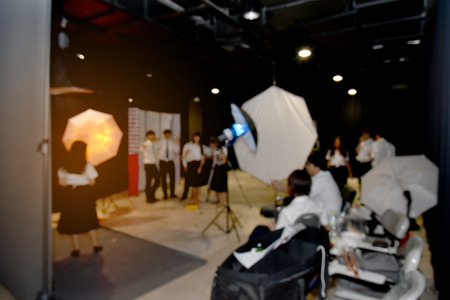 Blurry image of student photographer team in studio working advertising with studio flash.