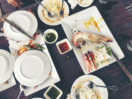 Delicious Grilled Giant River Prawn with pieces of chilli and parsley on white dish with soy sauce in small bowl in centre, on wooden table at restaurant,view from above. Thai Style Food. vintage toneの写真素材