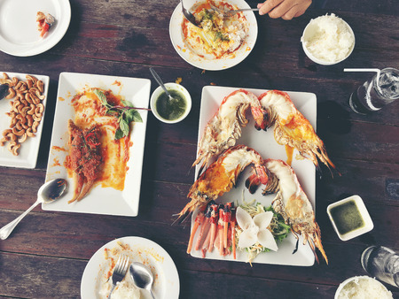 Delicious Grilled Giant River Prawn with pieces of chilli and parsley on white dish with soy sauce in small bowl in centre, on wooden table at restaurant,view from above. Thai Style Food. vintage toneの写真素材