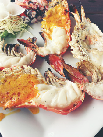 Delicious Grilled Giant River Prawn with pieces of chilli and parsley on white dish with soy sauce in small bowl in centre, on wooden table,view from above. Thai Style Food.の写真素材