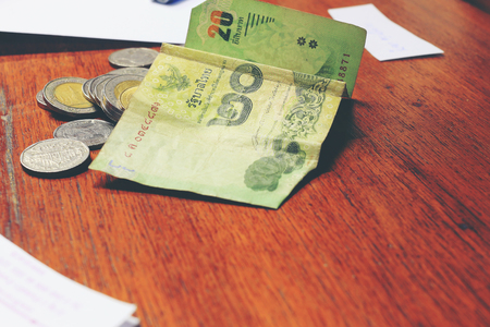 Calculator and money thai banknote with  white notebook paper, pen on wooden table at home office. The concept of financial planning, savings. vintage tone colour and motion blur moving of hand.の写真素材