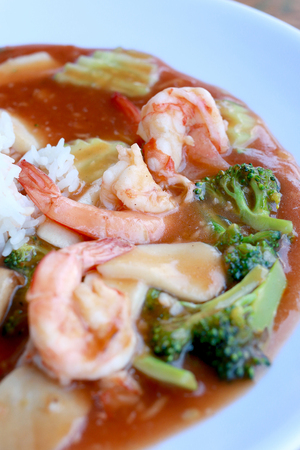 stir fried shrimp and Broccoli in thai red curry paste sauce with rice, Curry fried shrimps and cooked rice in white dish closeup on wooden table. Thai style food.の写真素材