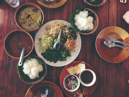 Variety of local vegetables having with curry rice noodle and mixed many kind of sauce for Thai rice noodle on wooden table famous food of Thailand. - A set of Thai cuisine. (Thai northern style).の写真素材