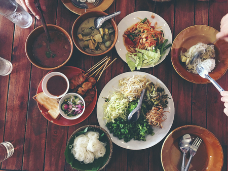 Delicious Asia food set on table. Rice noodles with spicy pork sauce and Pork satay, Grilled pork served with peanut sauce or sweet and sour sauce with vegetable. Top view. vintage toneの写真素材