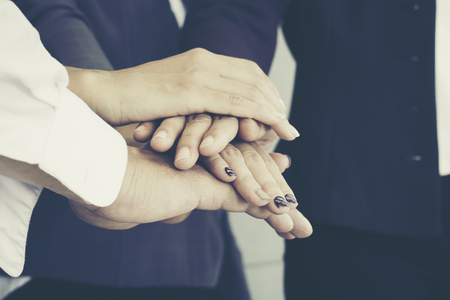 Close up of young business people putting and join their hands together. Team with stack of hands showing unity, collaboration and teamwork. Business teamwork concept.の写真素材