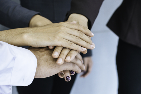 Close up of young business people putting and join their hands together. Team with stack of hands showing unity, collaboration and teamwork. Business teamwork concept.の写真素材