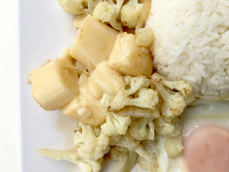 Stir Fried Tofu in Chinese Style,Deep Fried Tofu with Gravy Sauce ,Stir fried tofu with cauliflower and thai style fried egg in white plate on white background. Vegetarian Food, healthy food.の写真素材
