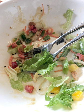 Dirty dish after eating caesar salad with vegetables and greens in white blow withの写真素材