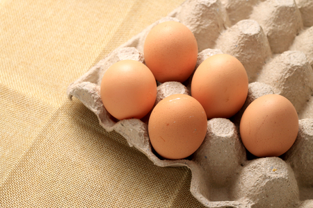 Fresh chicken eggs In the thirty box paper and have empty space for egg on cream fabric background.の写真素材