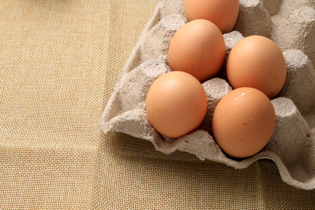 Fresh chicken eggs In the thirty box paper and have empty space for egg on cream fabric background.の写真素材