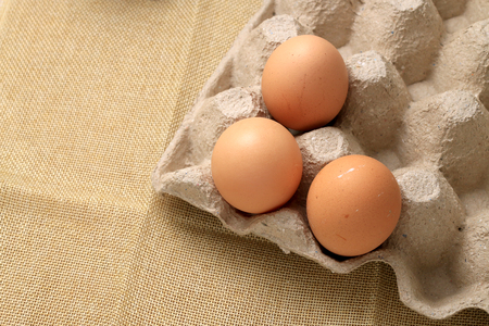 Fresh chicken eggs In the thirty box paper and have empty space for egg on cream fabric background.の写真素材