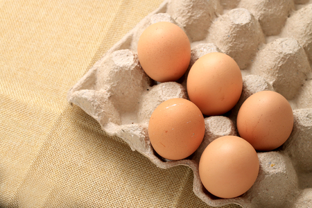 Fresh chicken eggs In the thirty box paper and have empty space for egg on cream fabric background.の写真素材