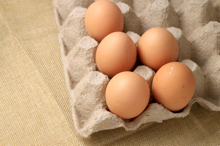 Fresh chicken eggs In the thirty box paper and have empty space for egg on cream fabric background.の写真素材