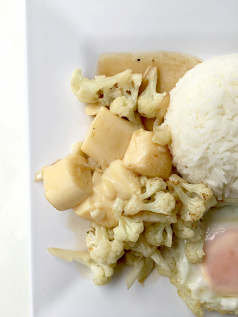 Stir Fried Tofu in Chinese Style,Deep Fried Tofu with Gravy Sauce ,Stir fried tofu with cauliflower and thai style fried egg in white plate on white background. Vegetarian Food, healthy food.の写真素材