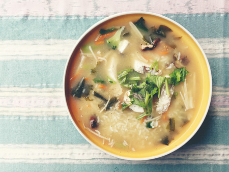 Homemade rice soup with vegetables and king fish in white bowl. Thai style food.の写真素材