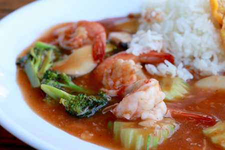 stir fried shrimp and Broccoli in thai red curry paste sauce with rice, Curry fried shrimps and cooked rice in white dish closeup on wooden table. Thai style food.の写真素材