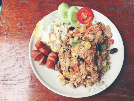 American style breakfast set, fried rice and the style fried egg and sausage in white dish  on wooden table. Thai food. vintage tone color.の写真素材