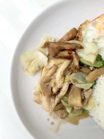 Stir-fried mix vegetables,  mushroom and herb with steam rice and thai fried egg style in white plate on white background. thai fast food make by order.の写真素材