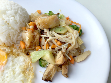 Stir fry yellow tofu and vegetable with rice and fried egg in white dish on white background for celebrate Chinese new year festival. Healthy food. Thai food.の写真素材