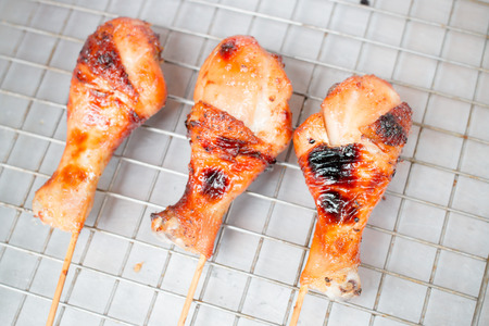 Grilled chicken leg on the grille local stainless dishes at The street market. Thai style food.の写真素材
