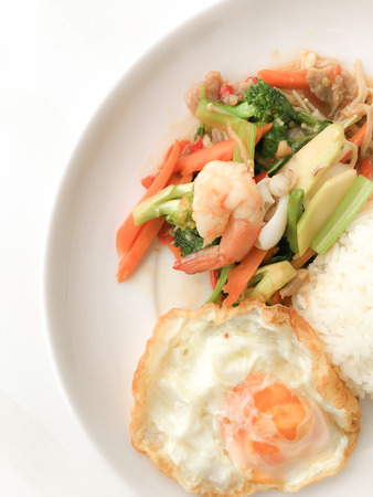 Fried Savory sauteed mixed vegetables with shimp and fried egg served with rice in white dish on white background as Thai homemade meal or recipe in the restaurant. Thai style food.の写真素材