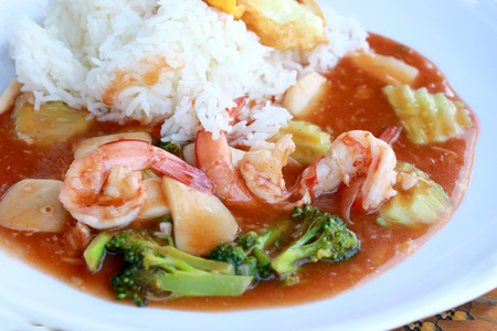 stir fried shrimp and Broccoli in thai red curry paste sauce with rice, Curry fried shrimps and cooked rice in white dish closeup on wooden table. Thai style food.の写真素材