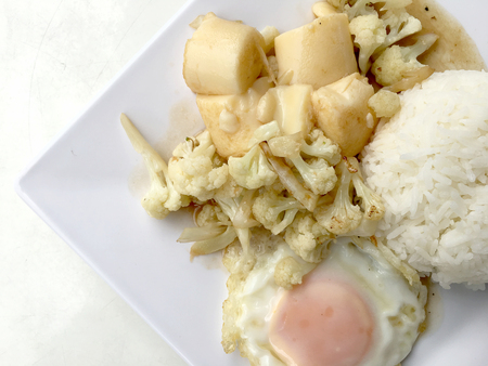 Stir Fried Tofu in Chinese Style,Deep Fried Tofu with Gravy Sauce ,Stir fried tofu with cauliflower and thai style fried egg in white plate on white background. Vegetarian Food, healthy food.の写真素材