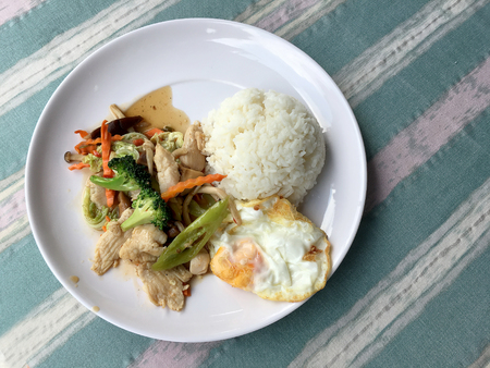 stir-fried vegetables with thai jasmine rice and fried egg in white dish as food for people who need control fat.の写真素材