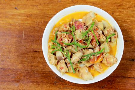 Northern Thailand local food called Kaeng Khanun-on is cooking like a young jack fruit soup with pork spare rib Thai herb, Climbing Wattle, Acacia pennata, red eggplant in white bowl on wooden table.の写真素材