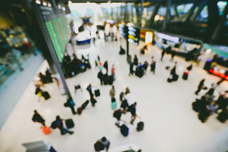 blurred image of crowd of travelling people or passenger walking with a luggage from flight in the international airport terminal with beautiful bokeh from the light,advertise & traveling concept.の写真素材