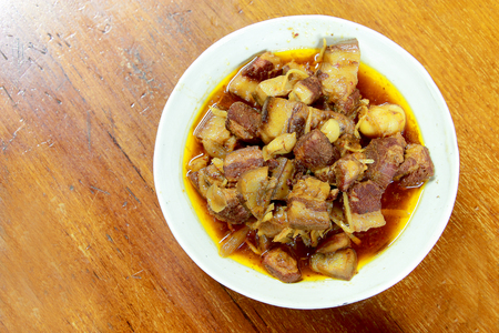 Northern Thailand local dish called Gaaeng Hang Laeh Moo is a Northern Style Hang Lay Curry with Thai herb, streaky pork, pickled onions in a bowl on wooden table. Thai traditional local northern foodの写真素材