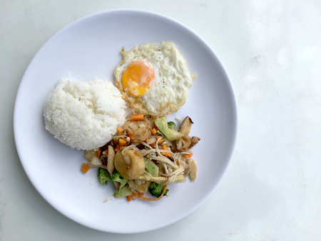Stir fry yellow tofu and vegetable with rice and fried egg in white dish on white background for celebrate Chinese new year festival. Healthy food. Thai food.の写真素材