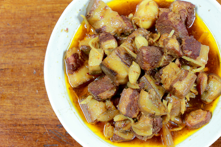 Northern Thailand local dish called Gaaeng Hang Laeh Moo is a Northern Style Hang Lay Curry with Thai herb, streaky pork, pickled onions in a bowl on wooden table. Thai traditional local northern foodの写真素材