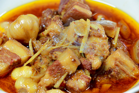 Northern Thailand local dish called Gaaeng Hang Laeh Moo is a Northern Style Hang Lay Curry with Thai herb, streaky pork, pickled onions in a bowl on wooden table. Thai traditional local northern foodの写真素材