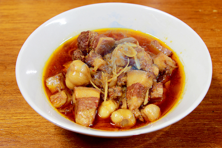 Northern Thailand local dish called Gaaeng Hang Laeh Moo is a Northern Style Hang Lay Curry with Thai herb, streaky pork, pickled onions in a bowl on wooden table. Thai traditional local northern foodの写真素材