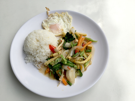 Stir mix vegetables  with gravy sauce and thai style fried egg in white plate on white background. Vegetarian Food, healthy food.の写真素材