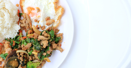 Stir-fried basil leave with minced pork, chicken, fried preserved egg and carrot, yellow corn, Broccoli with rice and fried egg in white dish on white background. Thai style food.の写真素材