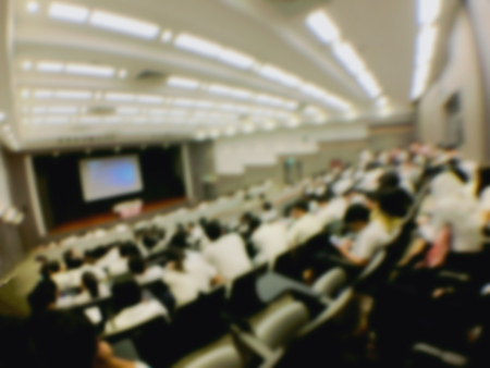 Education concept, Abstract blurred background image of students and business people  studying and discuss in large hall profession seminar with screen and projector for showing information.の写真素材