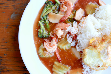 stir fried shrimp and Broccoli in thai red curry paste sauce with rice, Curry fried shrimps and cooked rice in white dish closeup on wooden table. Thai style food.の写真素材