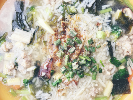 rice soup with vegetables, chickenin and pork in white bowl. Thai style food.の写真素材
