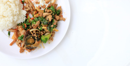 Stir-fried basil leave with minced pork, chicken, fried preserved egg and carrot, yellow corn, Broccoli with rice and fried egg in white dish on white background. Thai style food.の写真素材