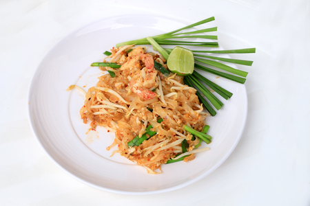 Pad Thai, stir-fried rice noodles with shrimp in white plate with slide lemon and green vegetable. The one of Thailand's national main dish. the popular food in Thailand. Thai Fried Noodlesの写真素材