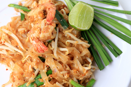 Pad Thai, stir-fried rice noodles with shrimp in white plate with slide lemon and green vegetable. The one of Thailand's national main dish. the popular food in Thailand. Thai Fried Noodlesの写真素材