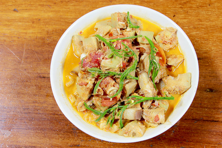 Northern Thailand local food called Kaeng Khanun-on is cooking like a young jack fruit soup with pork spare rib Thai herb, Climbing Wattle, Acacia pennata, red eggplant in white bowl on wooden table.の写真素材